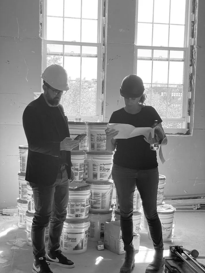 Architects in hard hats reviewing drawings on site
